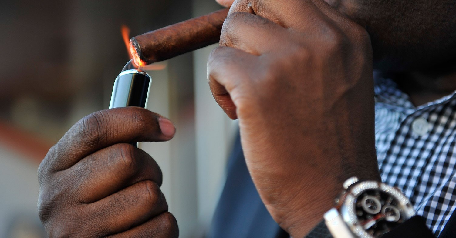 A person lighting a cigar with a premium lighter, representing the art of cigar pairing with the perfect lighting technique